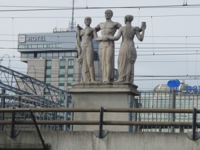 Gezien over de brede stationsinrit heen: Links het hoge NH Hotel, <br />dichterbij rechts (slecht zichtbaar door het hekwerk) het dak van het Park Plaza.